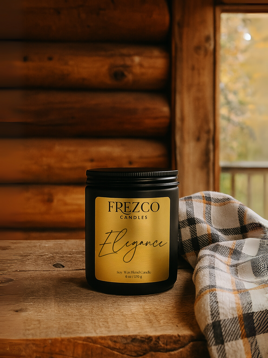 Frezco Candles 'Elegance' candle on a wooden table, next to a piece of flannel, in a cabin setting.