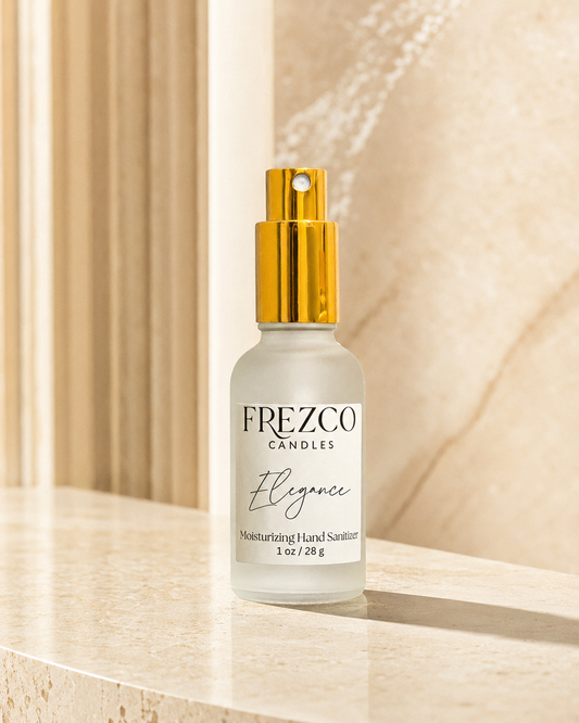 A bottle of Frezco Candle Elegance moisturizing hand sanitizer with a gold pump and frosted glass bottle, set on a beige marble surface with a warm, softly lit background.