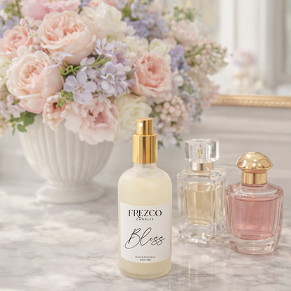 Frezco Bliss candle with two other candles on a marble surface with flowers in the background