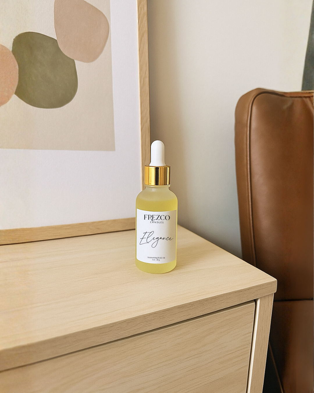 Frezco Elegance skincare serum bottle on a wooden surface with a blurred abstract painting in the background.