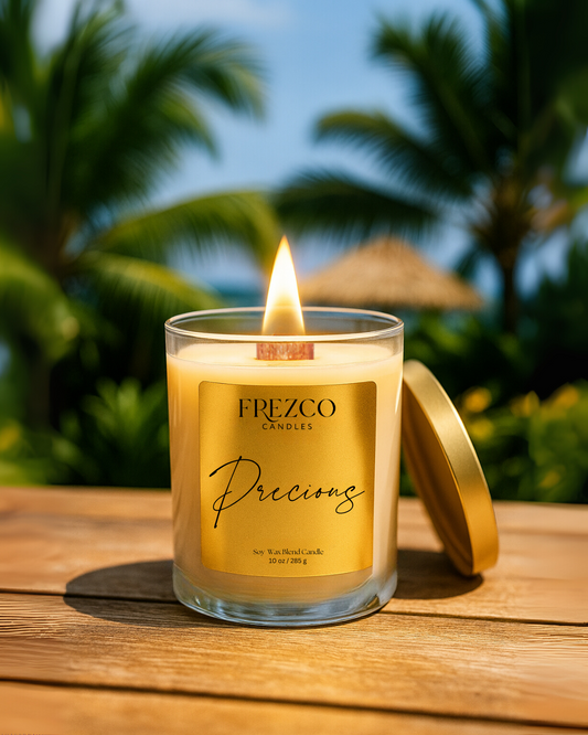 Frezco Candles 'Precious' candle on a wooden surface with palm trees in the background