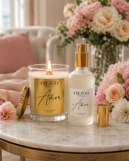 Frezco Amor candle and spray bottle on a marble table with flowers in the background
