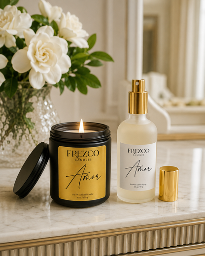 Frezco Amor candle and spray on a marble surface with flowers in the background