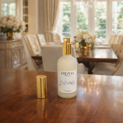 Frezco Candles Delectable spray bottle on a wooden table with a blurred background of a dining room.